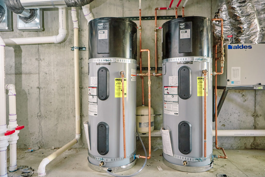 Two heat pump water heaters in a utility room of a multifamily building